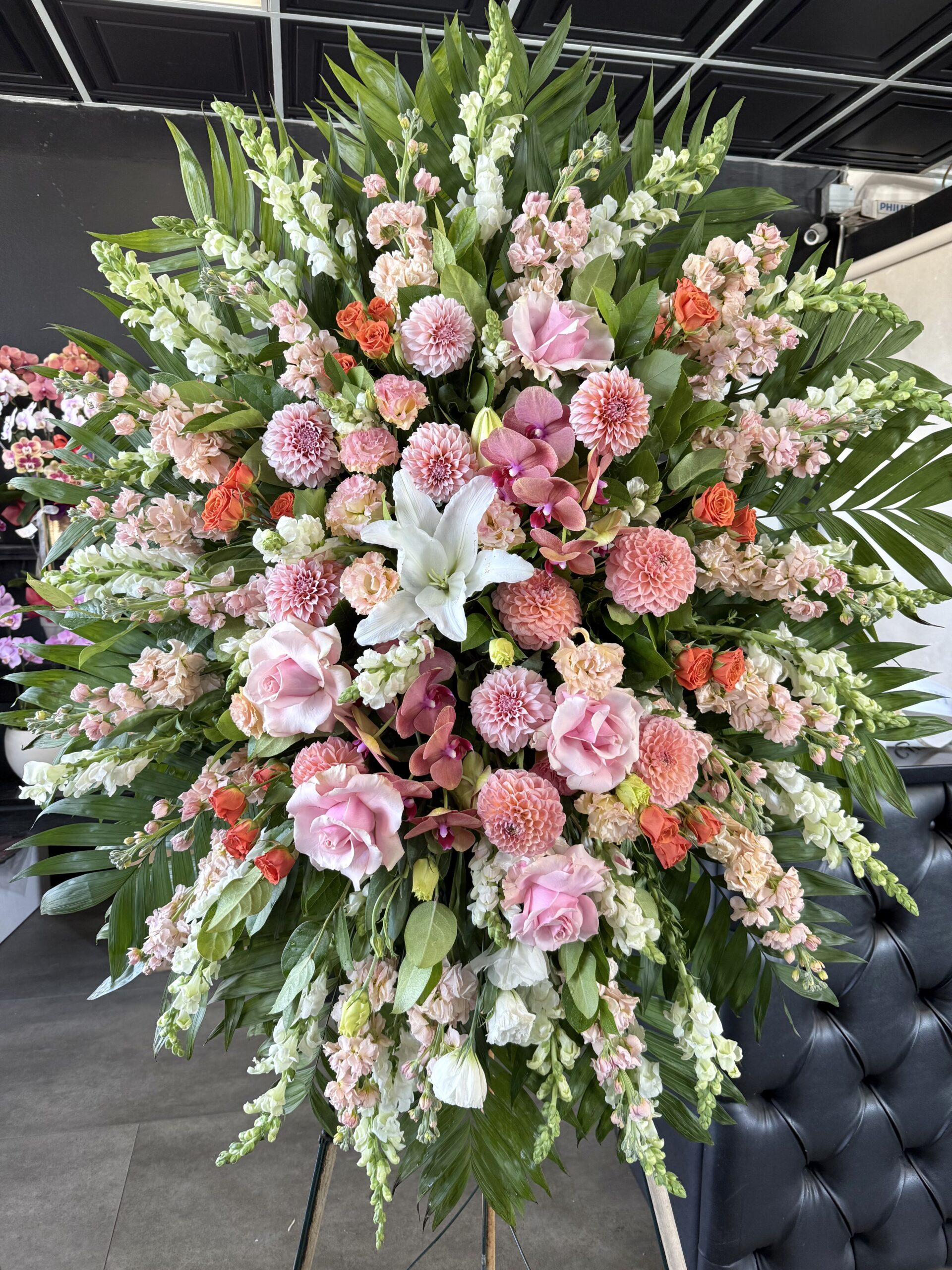 Blooming Memories Funeral Spray, a luxury floral tribute with pink roses, dahlias, and white lilies in an elegant arrangement.