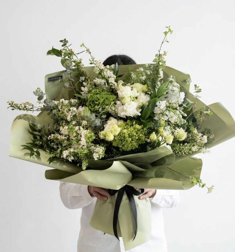 Bella Signora - Wrapped Bouquet featuring lush green hydrangeas, delicate white roses, and fragrant eucalyptus, elegantly arranged.