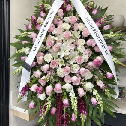Peaceful Dove Meaningful Funeral Spray Arrangement with pink and white roses, lilies, and snapdragons on a wooden stand.