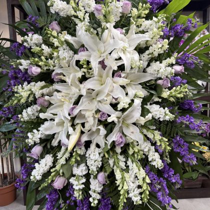 Oceanic Memories Funeral Spray - Serene Tribute featuring white lilies, purple delphinium, and lavender roses.