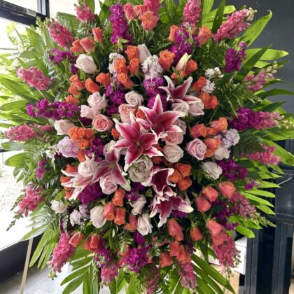 Wildflower Tribute Funeral Spray - Elegant Remembrance featuring vibrant pink lilies, orange roses, and purple stock flowers.