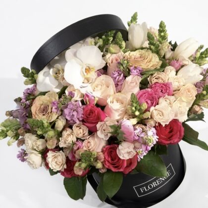 Luxurious arrangement of pink, white, and lavender flowers in an elegant black hat box.