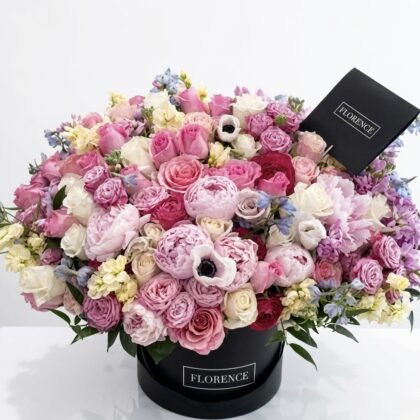 Luxurious arrangement of pink and white roses, peonies, and delicate blooms in a chic black box.