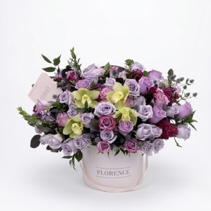 An elegant arrangement of lavender and purple roses, accented with vibrant green orchids and lush greenery.