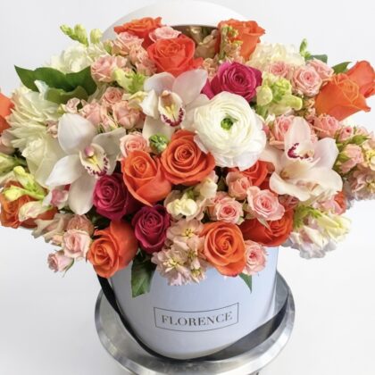 Luxurious floral arrangement featuring vibrant orange roses, delicate pinks, and elegant white orchids.