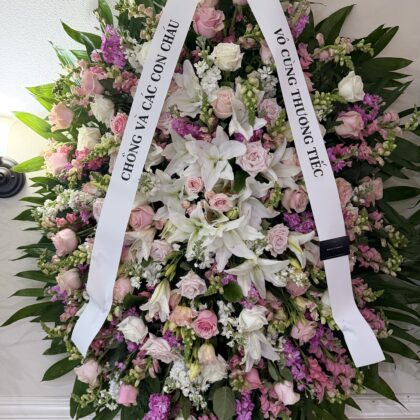 Morning Dew Funeral Spray for Comfort featuring white lilies, pink roses, and purple stock flowers in an elegant arrangement.