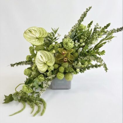 Fiore Segreto - Concrete Vase featuring lush green flowers, including orchids and textured foliage, elegantly arranged.