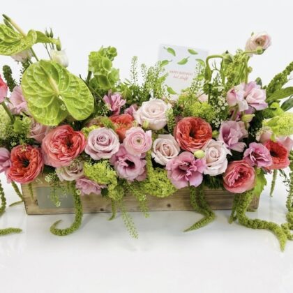 La Bellissima Rosa - Wood Pot features lush pink and green flowers elegantly arranged for a luxurious touch.