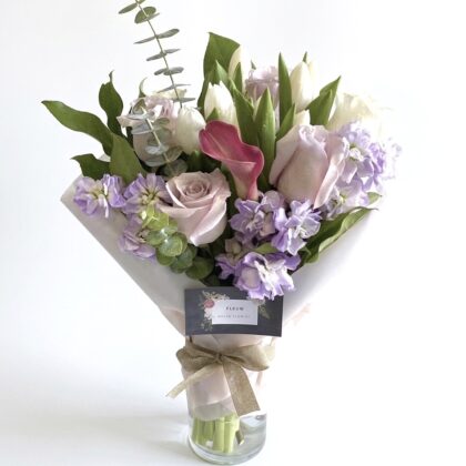 Carina Stella - Wrapped Vase featuring elegant pastel roses, tulips, and lilacs in a sophisticated arrangement.