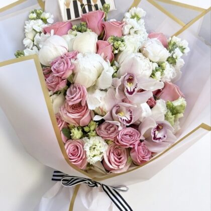 Elegant Bella Blush Peonies wrapped bouquet featuring soft pink peonies, roses, and delicate white orchids.