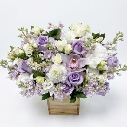 An elegant arrangement of lavender roses, white orchids, and delicate blooms in a luxurious display.