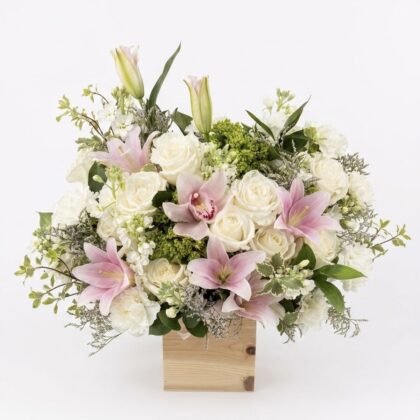 An elegant arrangement featuring white roses, pink lilies, and green accents in a premium wooden box.