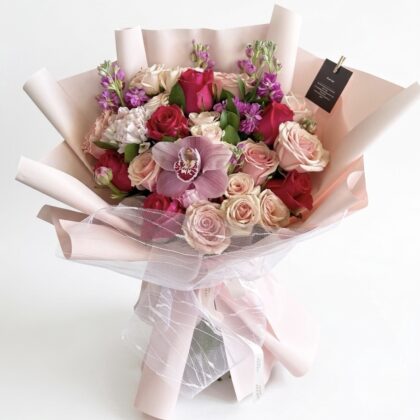 A luxurious bouquet featuring deep red roses, soft pink roses, and vibrant purple orchids, elegantly arranged.