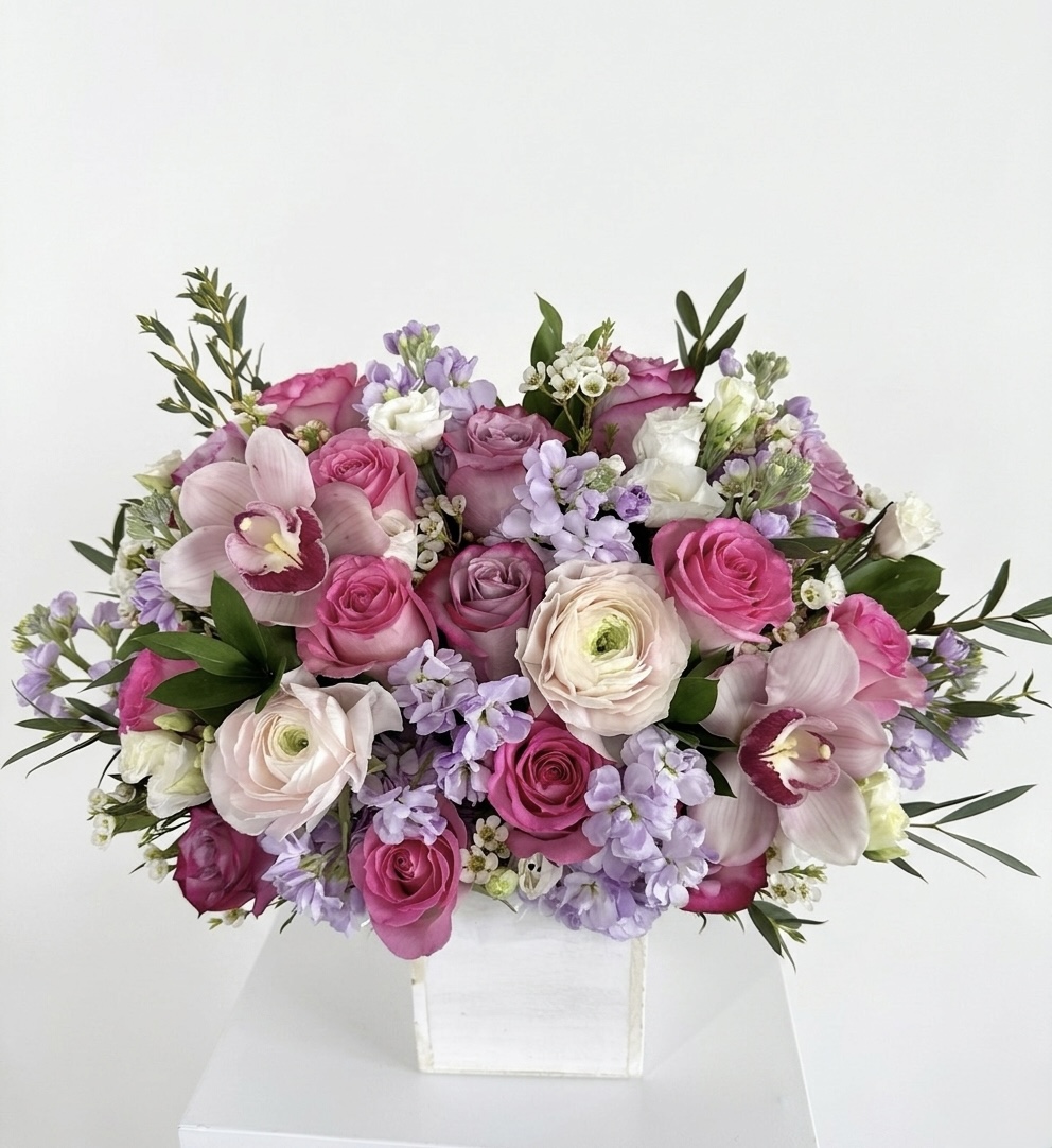 Luxurious arrangement of pink roses, delicate lilacs, and elegant orchids in a premium white box.