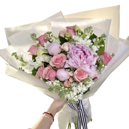 An elegant bouquet featuring soft pink roses, peonies, and delicate white flowers, beautifully arranged.