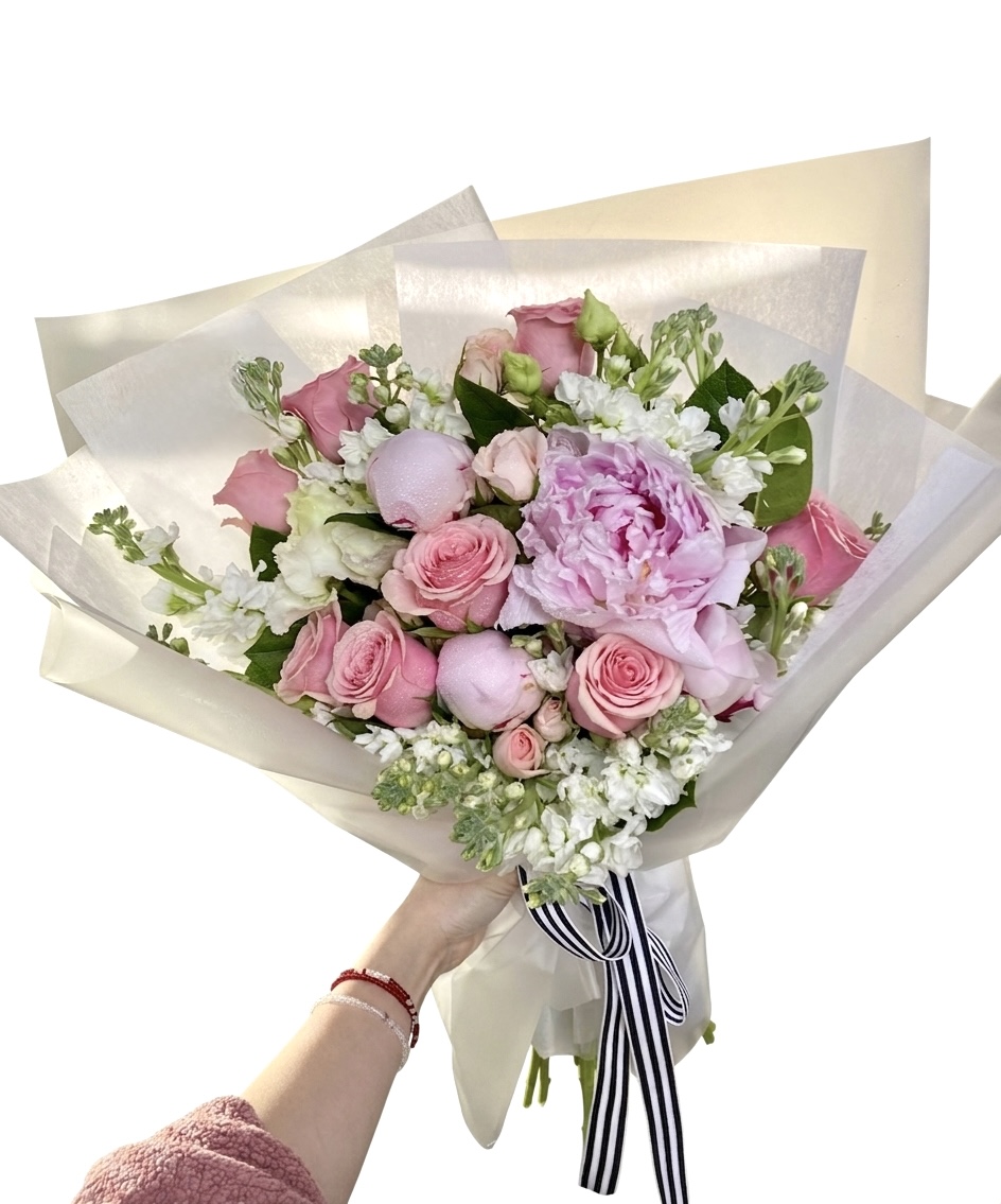 An elegant bouquet featuring soft pink roses, peonies, and delicate white flowers, beautifully arranged.