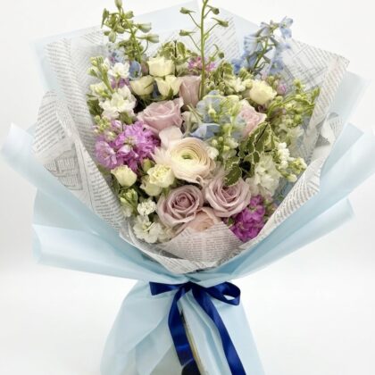 An elegant bouquet featuring soft pink roses, lavender blooms, and delicate white flowers, beautifully arranged.