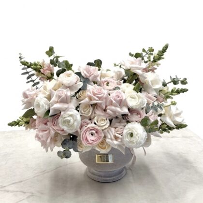 Luxurious arrangement of soft pink and white roses, complemented by delicate greenery, exuding elegance.
