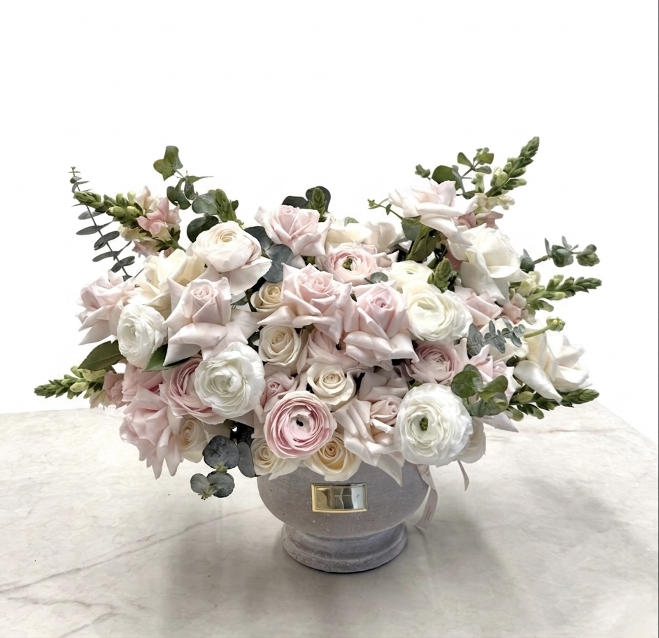 Luxurious arrangement of soft pink and white roses, complemented by delicate greenery, exuding elegance.