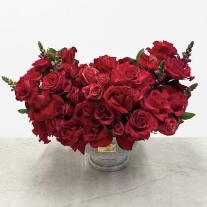 Luxurious arrangement of deep red roses and delicate snapdragons in a stylish vase, exuding elegance.