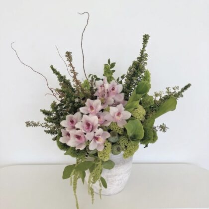 Matisse Meadow – Avant-Garde Ceramic Vase featuring pale pink orchids and lush green foliage in a textured stone vessel.