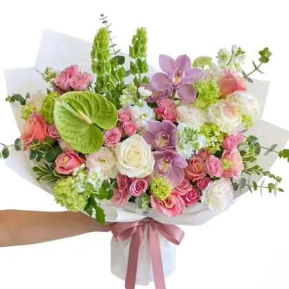 Maison De Beaute – Exquisite Wrapped Bouquet featuring pink roses, orchids, and green anthurium in white paper.