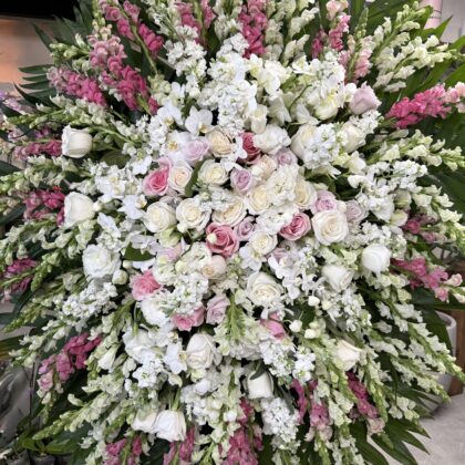 Sweet Breeze Stunning Funeral Spray Tribute with white and pink roses, snapdragons, and lush green palm leaves.
