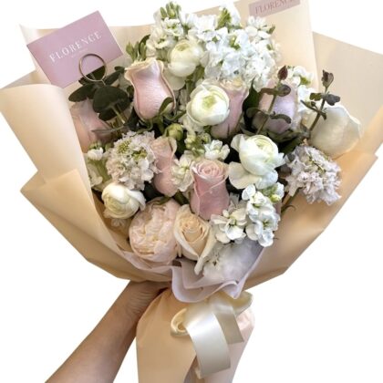 Amore Mio – Soft Pastel Wrapped Bouquet featuring delicate pink roses, white ranunculus, and stock in elegant paper.