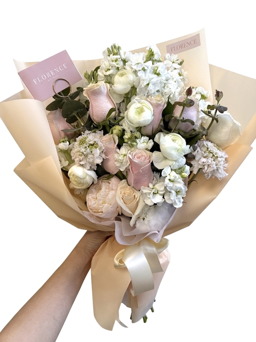 Amore Mio – Soft Pastel Wrapped Bouquet featuring delicate pink roses, white ranunculus, and stock in elegant paper.