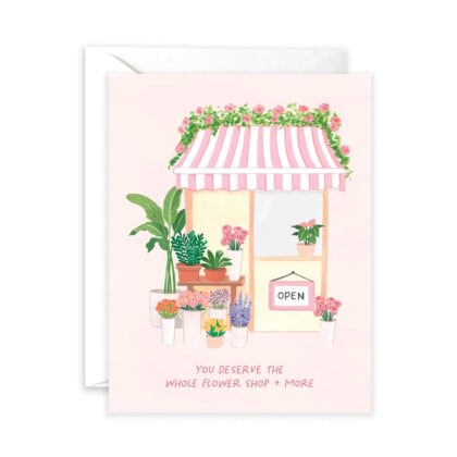 A charming greeting card featuring a boutique flower shop with pink striped awnings and assorted potted floral arrangements.