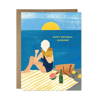 Happy Bday Sunshine - Bright Greeting Card featuring a woman in a swimsuit relaxing by the sea at sunset.