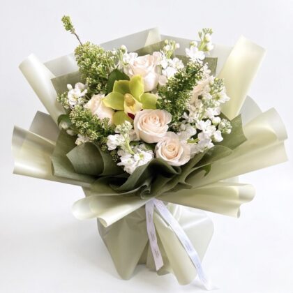 Modern Matcha Latte Wrapped Bouquet featuring cream roses, white stock, and a lime green orchid in elegant paper.
