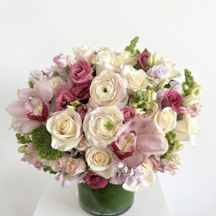 Reverie De Soie – Elegant Floral Arrangement featuring blush roses, ranunculus, and orchids in a glass vase.