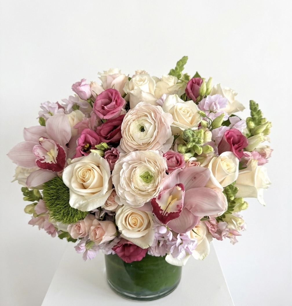 Reverie De Soie – Elegant Floral Arrangement featuring blush roses, ranunculus, and orchids in a glass vase.