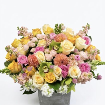 Cheeky Girl – Vibrant Floral Concrete Vase featuring a lush arrangement of yellow, pink, and peach blooms in a grey pot.