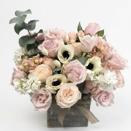 La Petite Parisienne – Rustic Floral Elegance featuring soft pink roses, white anemones, and eucalyptus in a wood pot.