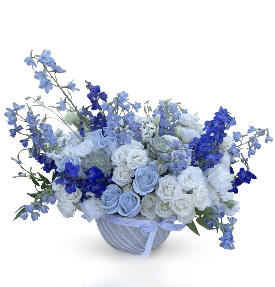 Cherie Bisou – Coastal Elegance Floral Vase featuring blue delphiniums, white roses, and succulents in a ceramic bowl.