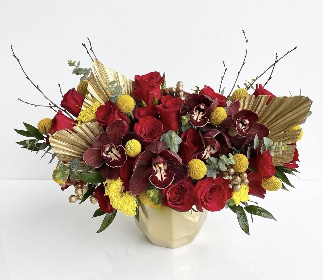 Regal Sweet Prosperity Ceramic Vase featuring deep red roses, dark orchids, yellow billy balls, and gold palm leaves.