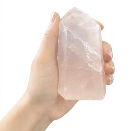 A hand holding an Elegant Rose Quartz Healing Tower for Your Space, featuring soft pink hues and natural crystal facets.