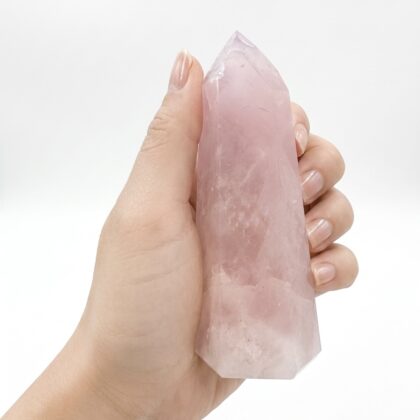 A hand holding a Charming Rose Quartz Healing Tower for Home Decor against a clean white background.