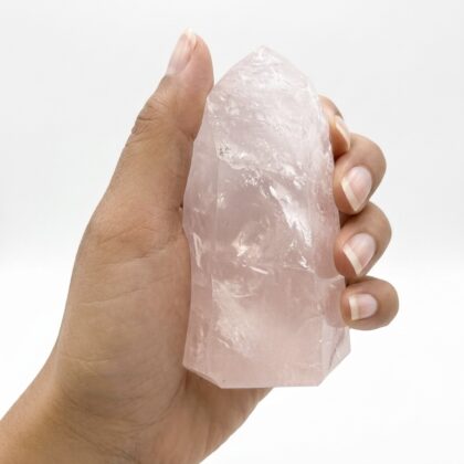 A hand holds a Radiant Rose Quartz Healing Tower for Inner Peace against a clean, white background.
