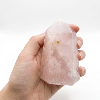 A hand holding a polished Rose Quartz 6 crystal tower, perfect as a Chic Rose Quartz Healing Tower for Home Ambiance.