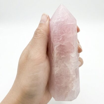 A hand holding a Beautiful Rose Quartz Healing Tower for Positive Energy against a clean white background.