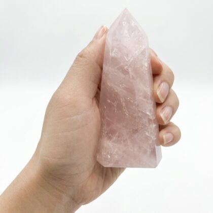 A hand holds an Elegant Rose Quartz Healing Tower for Your Space, featuring soft pink hues and natural crystalline textures.