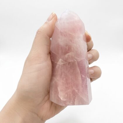 A hand holds a Rose Quartz 14 &ndash; Exquisite Crystal Tower, showcasing its translucent, soft pink crystalline structure.