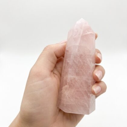 A hand holding a Rose Quartz 16 – Elegant Crystal Tower against a clean, white background.