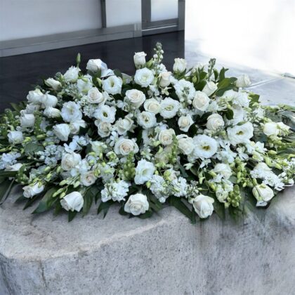 Cascading Sunset Elegant White Casket Spray featuring lush white roses and lisianthus arranged in a sophisticated display.