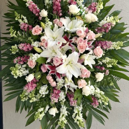 Pacific Memorial Funeral Spray with Radiant Lilies featuring white lilies, pink roses, and snapdragons on a palm leaf base.