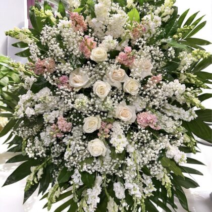 Warm Memories &ndash; Elegant Funeral Spray featuring white roses, blush stock, and baby's breath with lush green palm leaves.