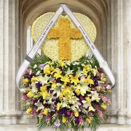 The Legacy – Heart Cross Double Layer Spray features a yellow floral cross on a white heart base with vibrant mixed blooms.